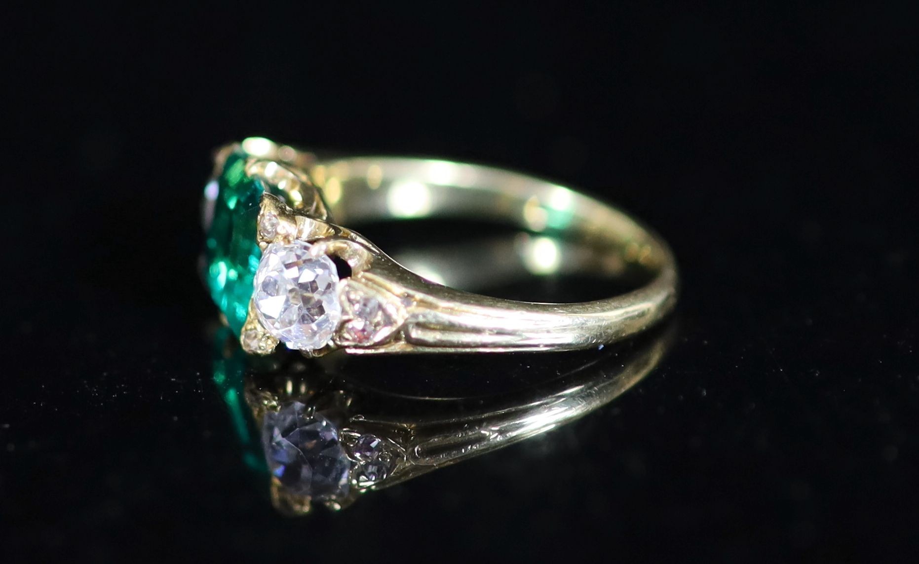 A good early 20th century gold, single stone trap cut emerald and two stone old cut diamond set ring